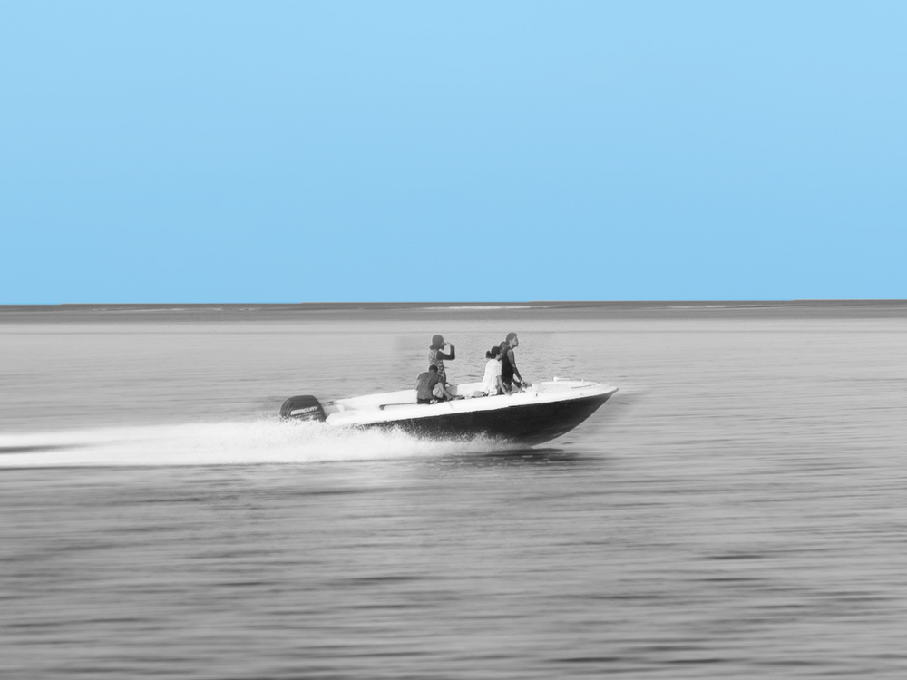 Motorbåt med passagerare kör snabbt på sjön.