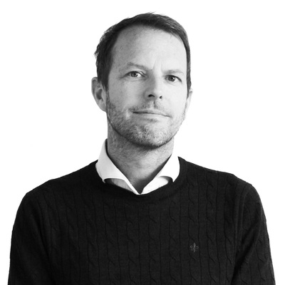 Mikael Ene i svartvitt porträtt. Ser rakt fram. Bär tröja.