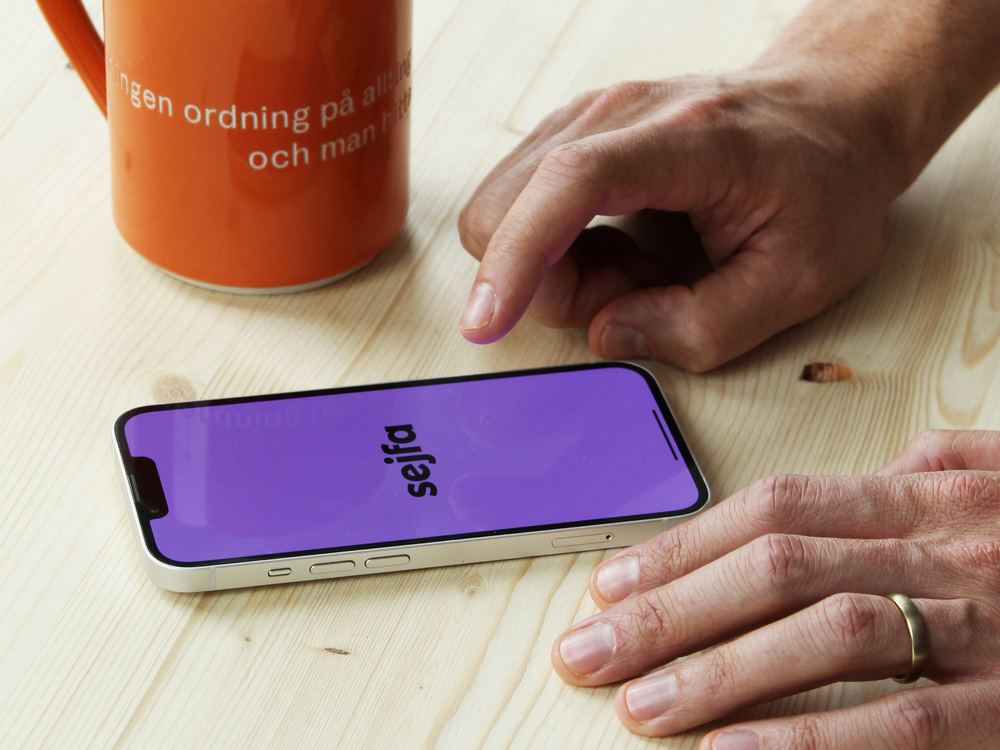 Visar Sejfa-appens purpurlila gränssnitt på en mobiltelefon.