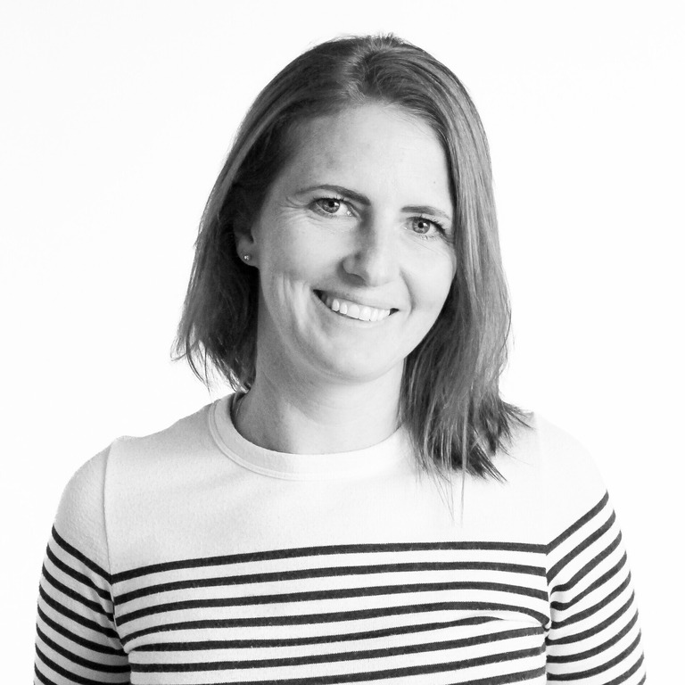 Elin Ax i svartvitt porträtt. Hon ler mot kameran och bär en randig tröja.